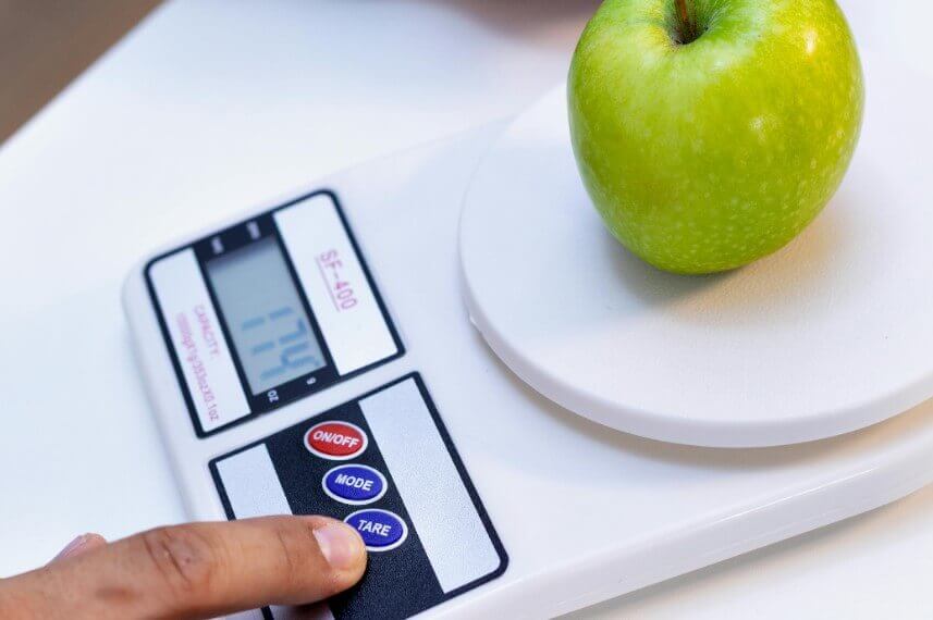 Pessoa usando a função tara da balança digital